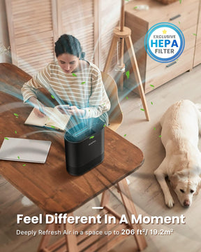 A woman sits at a wooden desk, writing in a notebook, next to a black Renpho Compact Air Purifier 068 Ozone Free with visible airflow visualization. A dog sleeps nearby on the floor. The device features a HEPA filter.